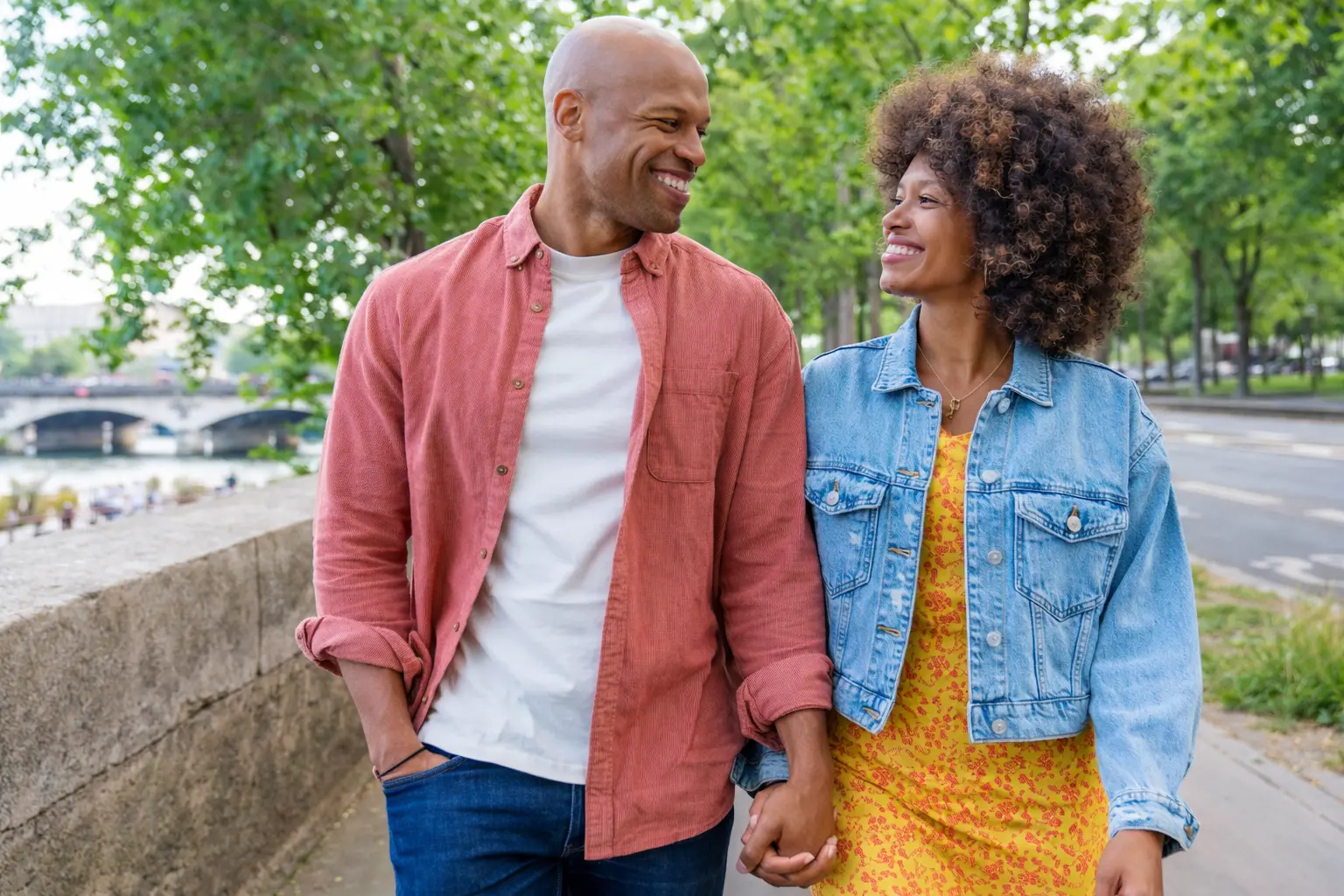 Couple walking hand in hand on a tree-lined street